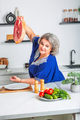 Beautiful woman holding a piece of fresh juicy meat tenderloin while cooking in the kitchen. Healthy and organic eating. Vitamin foods are good for your health.	
