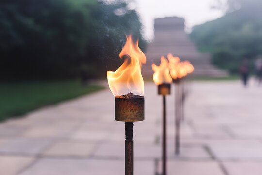 Flames flicker atop torches lined along stone path, creating mys
