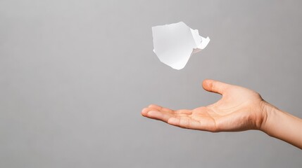 A hand releasing a floating, translucent object against a neutral background, symbolizing lightness and freedom.