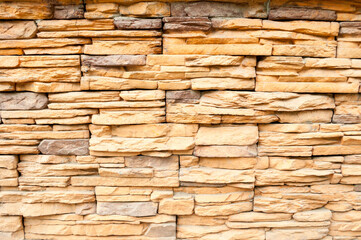 Obraz premium Stone background of decorative wall made of sandstone, stone texture, closeup of stone wall made with sand stone blocks