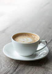 Cup of hot cappuccino coffee on table