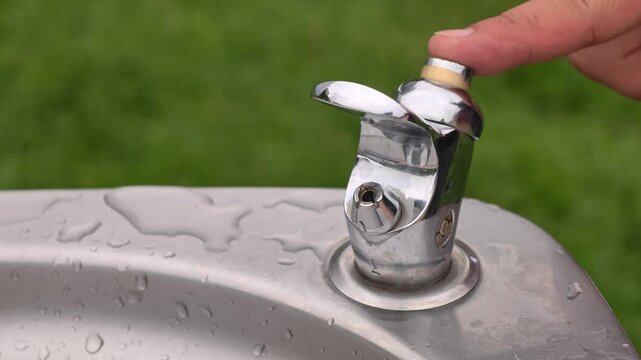 The nozzle of the outdoor drinker is spewing clean drinking water in a slow shot