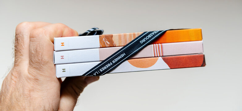Paris, France - Feb 17, 2025: A stack of three Henner Freres chocolate bars wrapped with a black ribbon labeled Strasbourg, showcasing elegant packaging and branding in a close-up hand-held shot.