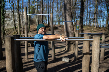 Wide-angle shot of determined mid-aged man in blue athletic wear performing stretching routine at...