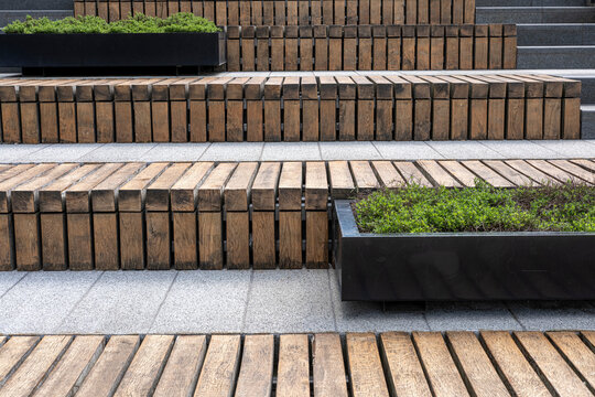 Public space with tiered wooden benches and integrated planters, contemporary urban design.