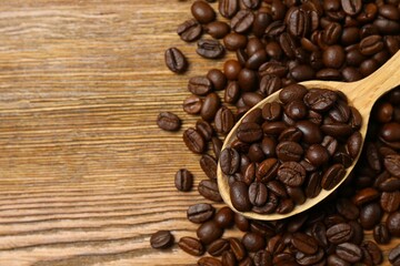 Ffresh coffee beans in a spoon on wooden background