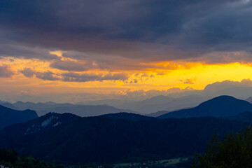 Obraz premium Silhouette of mountain range with partly cloudy sky at sunset.