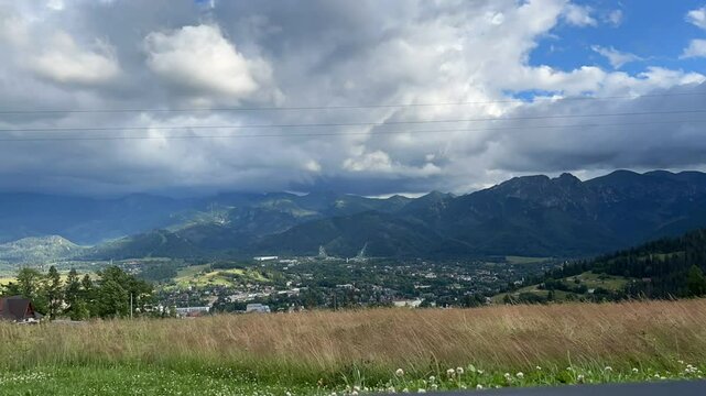 Mountain panorama of high mountains in the summer in sunny weather with cloud clouds. Mountain panorama from the height of the mountain. In the gorge of the city of the city.