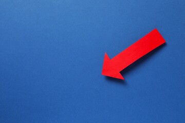 Paper arrow on color background, top view