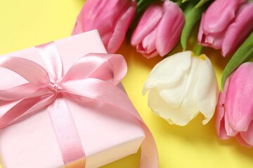 Beautiful fresh tulips with gift box on color background