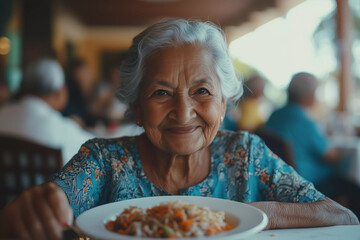 Senior Indian female having lunch at nursing home. Old woman eating food in local community