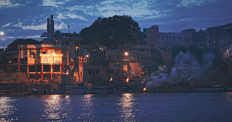 Fototapeta premium Varanasi, India. Funeral Rites Of Cremation At Harishchandra Ghat. Harishchandra Ghat Is One Of Only Two Ghats Serving As Cremation Sites Along Ganges River. Fire That Never Stops Sends Souls To