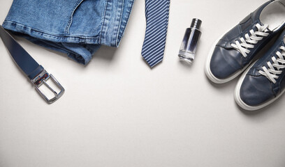 Blue jeans with a belt and other objects on the grey background.