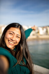 Happy woman taking a selfie near the beach