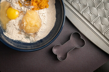 Making crunchy homemade baked healthy dog treat biscuits, sweet potato, applesauce, egg, whole wheat flour in a blue bowl.