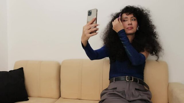 Video of a Latina woman combing her hair with her cell phone