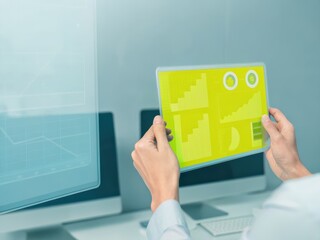 A person interacts with a translucent digital display, showcasing colorful geometric patterns in a modern tech environment.