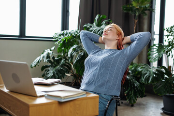 Happy relaxed female worker rest in chair distracted from computer work. Mindfulness and wellbeing...