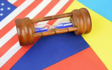 Hourglass on United States, Russian and Ukranian flags close up. Negotiations and relationship...