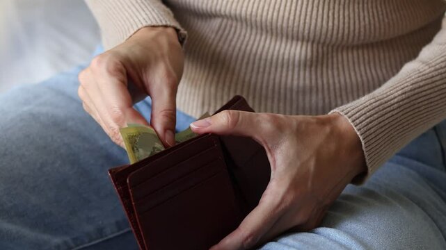 Woman's hands holding leather wallet with Nepalese rupee (NPR) cash money banknotes. Concept of saving money for retirement, cash settlement, financial success, literacy and income planning in Nepal.