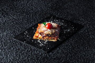 Appetizer of baked eggplant sprinkled with parmesan cheese on a plate in the background.