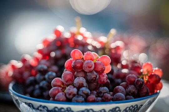 Close-up of fresh red grapes in a decorative bowl, showcasing their vibrant color and natural shine. - Powered by Adobe