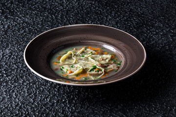 Mushroom Dumpling Soup in plate on black background. High quality photo.