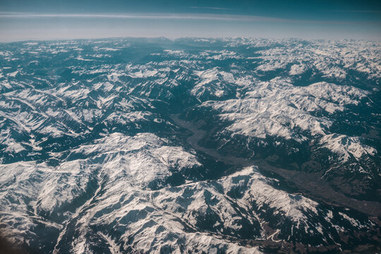 Mountain view from an airplane window, snow covered mountains in The Alps
