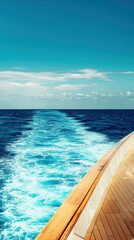Boat wake on a bright blue ocean under a clear sky with wood decking in foreground