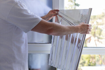 Man holding unrolled windows sun protection film.