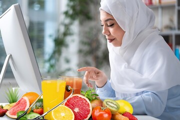 Young nutritionist working on laptop at table in office,