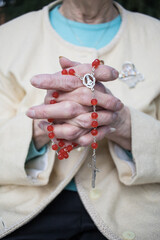 close-up Rosary in praying clasped wrinkled hands of elderly female. christianity. Horizontal