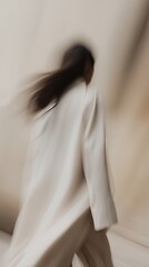 Abstract image of a woman in motion, capturing a sense of dynamic movement and soft, neutral tones.
