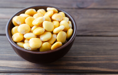 Lupin beans in a brown bowl on a wooden table. Italian food. Type of legumes. Healthy food concept. Horizontal orientation. Selective focus. Copy space.