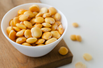 Lupin beans in a white bowl on a cutting board on a white table. Italian food. Type of legumes. Healthy food concept. Horizontal orientation. Selective focus. Copy space.