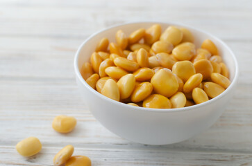 Lupin beans in a white bowl on a wooden table. Italian food. Type of legumes. Healthy food concept. Horizontal orientation. Selective focus.