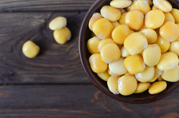 Lupin beans in a brown bowl on a wooden table. Italian food. Type of legumes. Healthy food concept. Horizontal orientation. Selective focus. Copy space. Top view