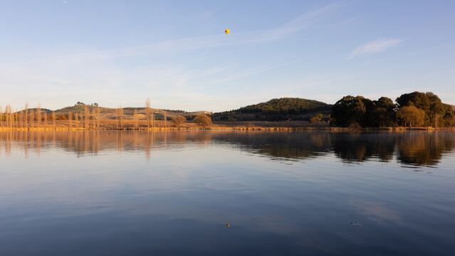 Landscape reflection in the lake during sunrise with hot air balloon in Canberra, Australia