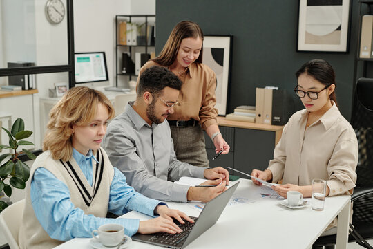 Candid shot of diverse business team working together during meeting in modern office discussing documents and analyzing data