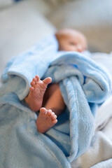 Newborn baby showing feet wrapped in blue blanket