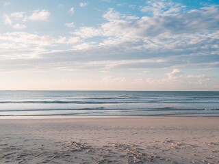 Obraz premium Serene beach view with gentle waves and soft clouds, evoking tranquility and peace.