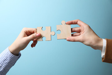 Business strategy and teamwork concept. Partners putting puzzle pieces together on light blue...