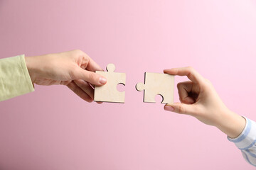 Business strategy and teamwork concept. Partners putting puzzle pieces together on pink background,...