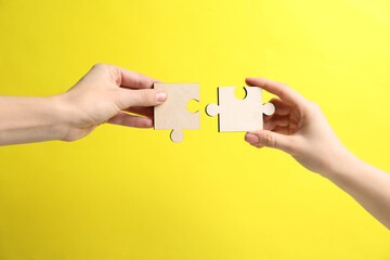 Business strategy and teamwork concept. Partners putting puzzle pieces together on yellow...