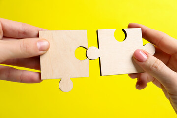 Business strategy and teamwork concept. Partners putting puzzle pieces together on yellow...