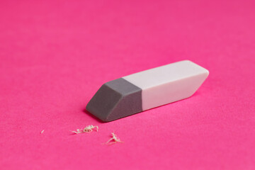 One eraser and scraps on pink background, closeup