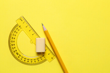 Eraser, pencil and protractor on yellow background, top view. Space for text