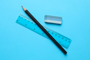 Eraser, pencil and ruler on light blue background, top view