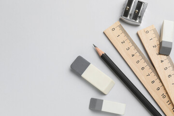 Erasers, pencil, sharpener and rulers on light background, top view. Space for text