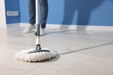 Woman cleaning floor with string mop indoors, closeup
